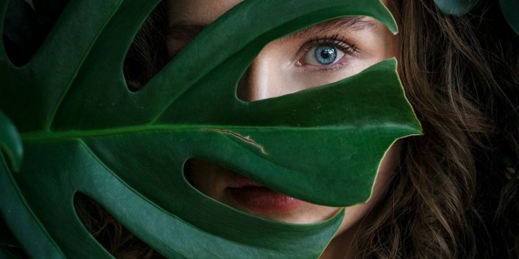 frau-mit-blatt-vor-dem-gesicht-gruen-natur-schoenheit-blaue-augen