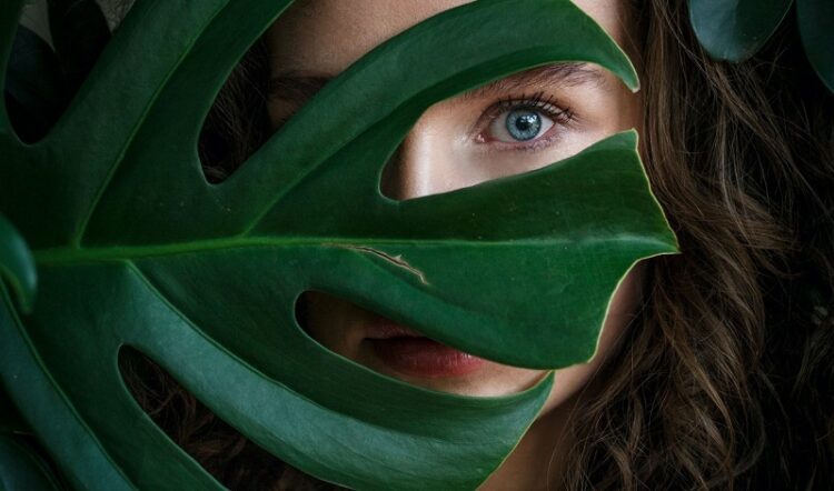 frau-mit-blatt-vor-dem-gesicht-gruen-natur-schoenheit-blaue-augen