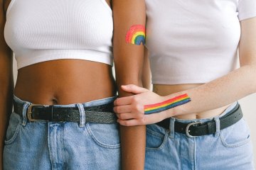 homophobie-wegkuscheln-zwei-junge-frauen-lesbisches-liebespaar-pride-flag